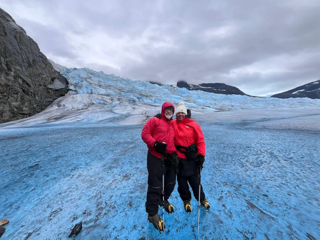 Couple standing on icy glacier landscape.