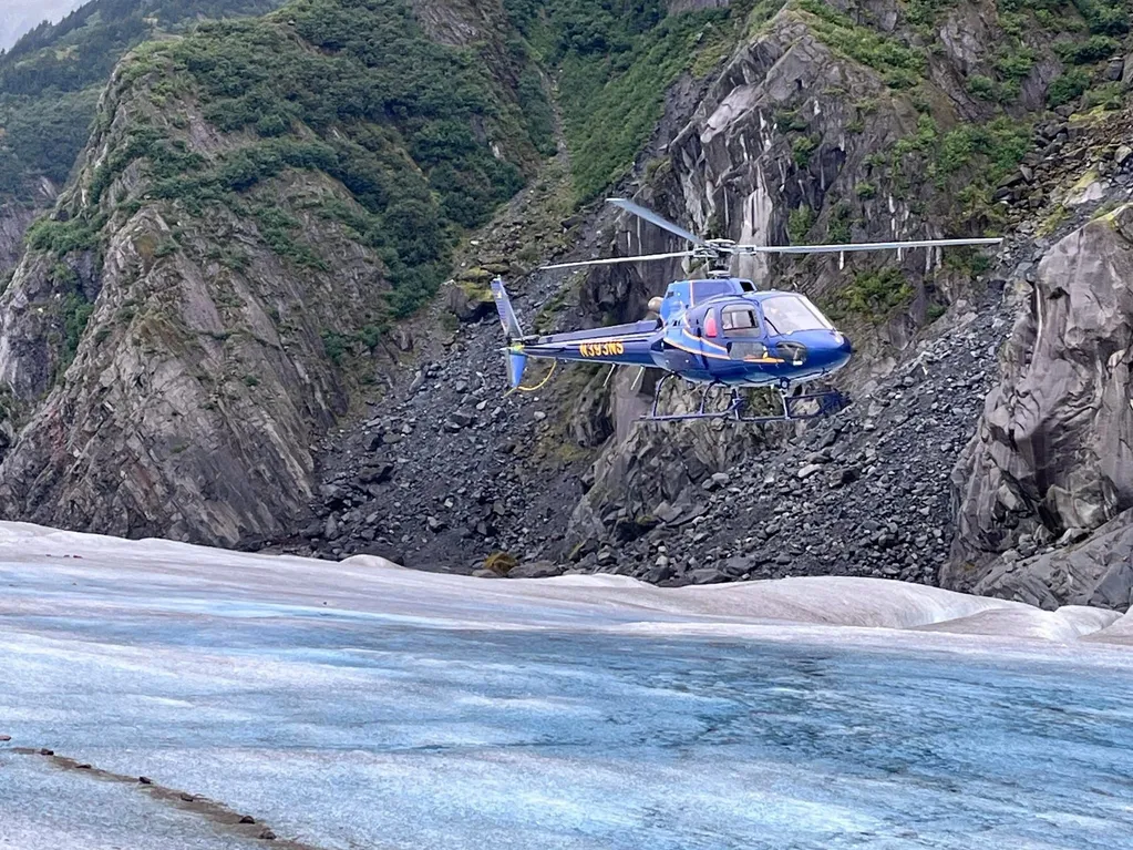 Blue helicopter over icy glacier terrain